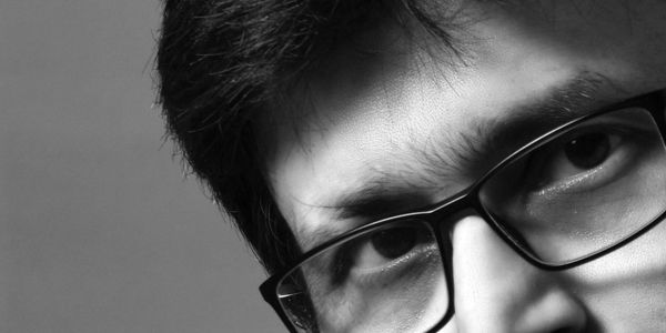 Black and white close-up portrait of a man with glasses and a mustache.