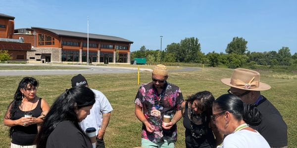 Group gathered outdoors around a basket, engaging in a shared activity on a sunny day.