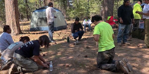 Group of people camping and preparing in a forest clearing.