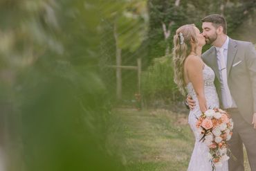 Bride and groom share a kiss in a vineyard.