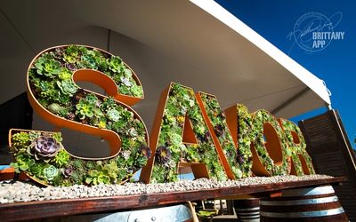 Large letters spelling 'SAVOR' decorated with succulents at an outdoor event.
