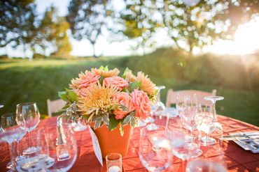Outdoor table with floral centerpiece and glassware at sunset.