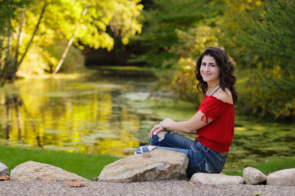 Young woman smiling by a peaceful pond.