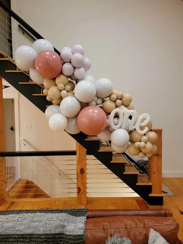 Custom color balloon garland with balloon phrase for a first birthday on a staircase