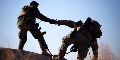 Marine pulling another Marine up over a hill.  Credit: Cpl Reece Lodder flickr.com