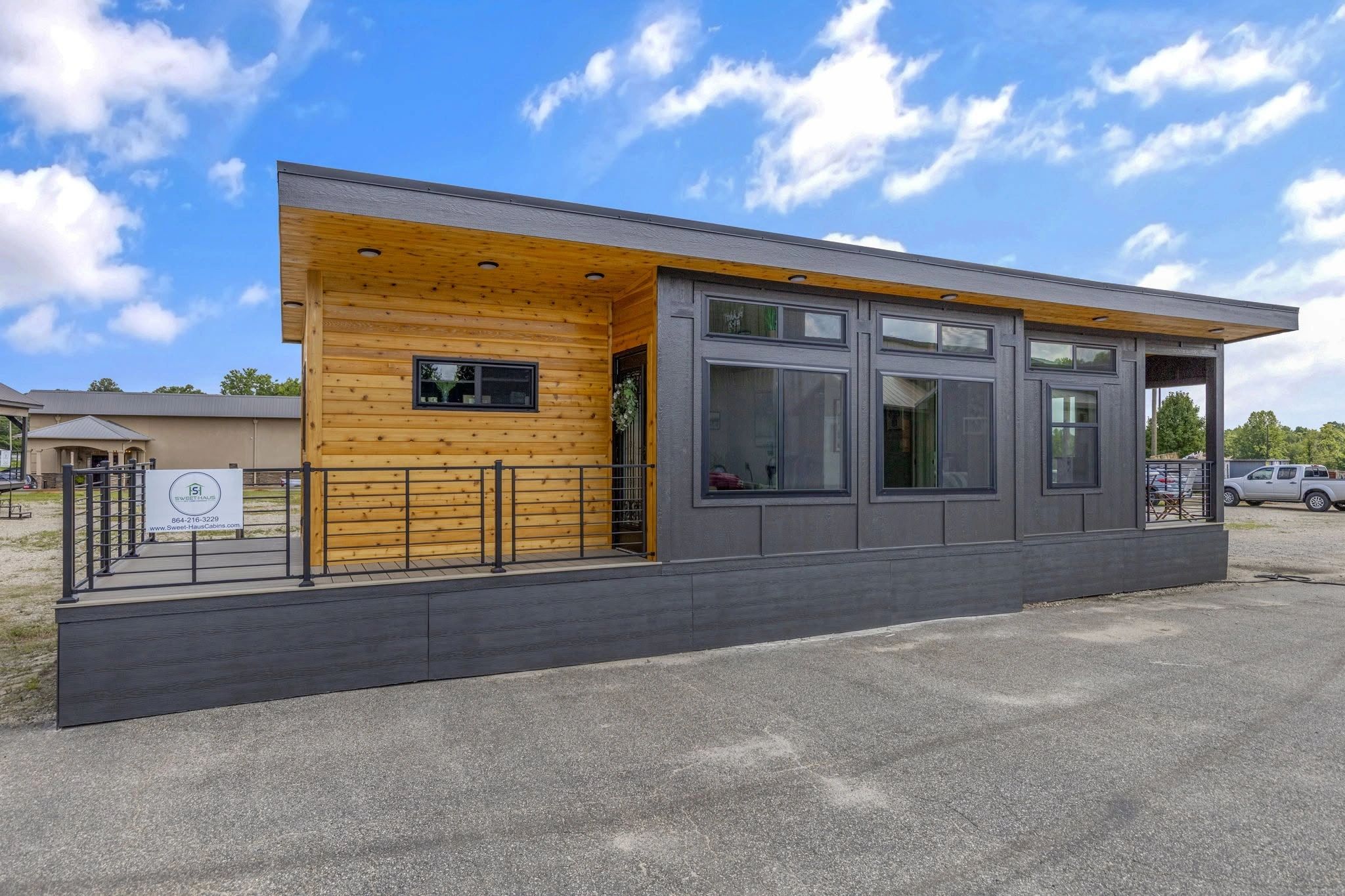 Modern tiny house with wood and dark panel exterior under a bright blue sky.