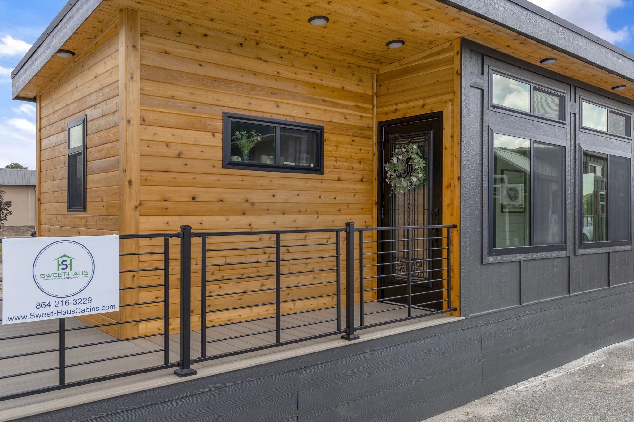 Modern tiny house with mixed wood and dark panel exterior and a black metal railing.