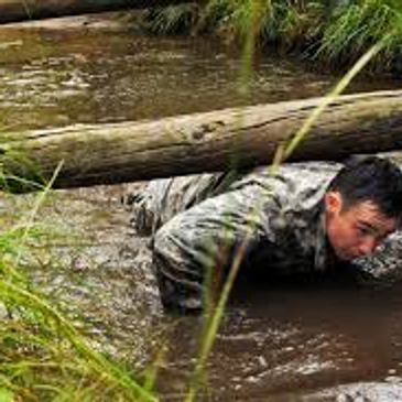 Soldier in water crawling under a log.