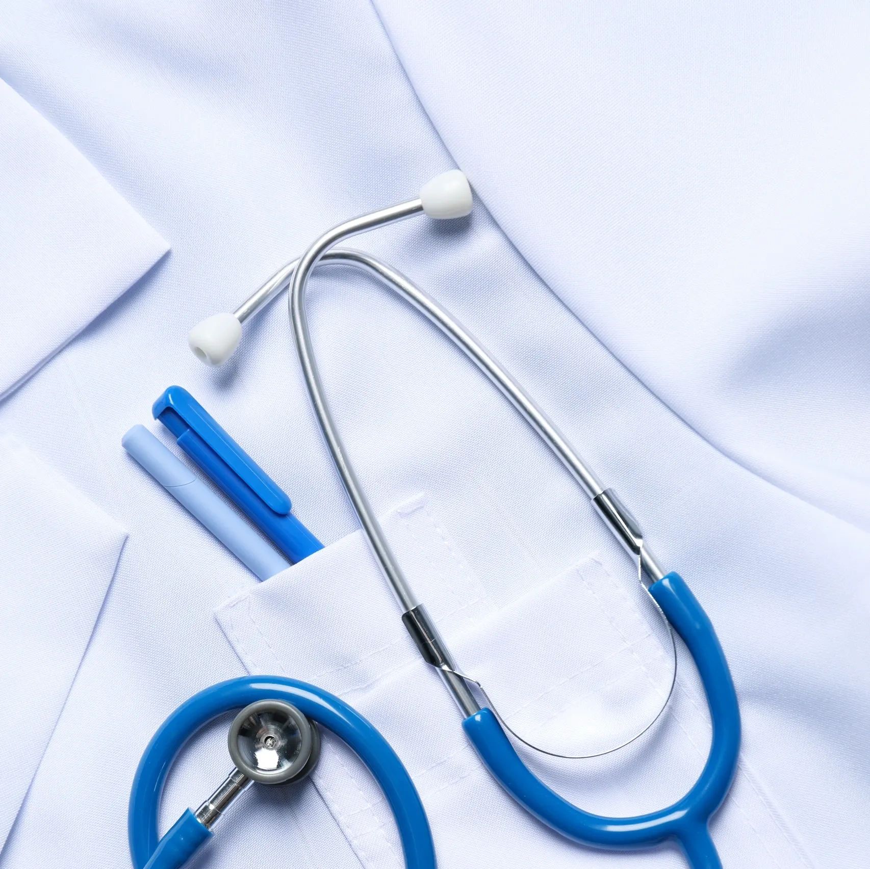 Stethoscope and pens in a white medical coat pocket.