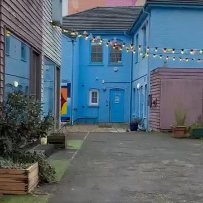 Colorful blue building with string lights above an empty street.