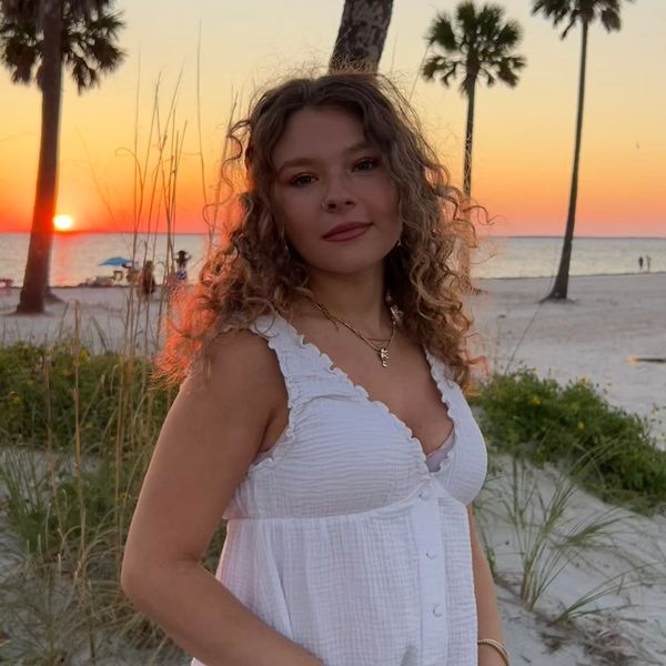 Woman in white dress at sunset beach.