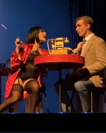 Two actors performing an intense scene at a table with a vintage telephone.