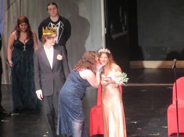 A crowning moment in a stage event with a queen and king.
