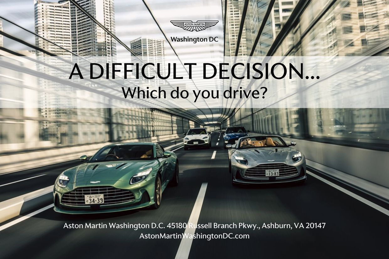 Two Aston Martin sports cars racing in a tunnel under city skyscrapers.