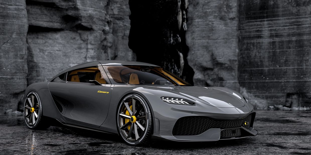 Sleek grey sports car with yellow accents parked on wet ground near rocky cliffs.