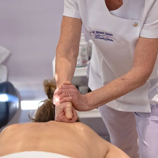 Massage Therapist applying a deep tissue technique to client's upper back while client is lying on t
