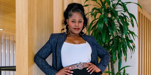 Confident woman in business attire with leopard print accents stands indoors, high fashion poses