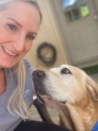 Woman smiling with a yellow Labrador dog looking up at her.