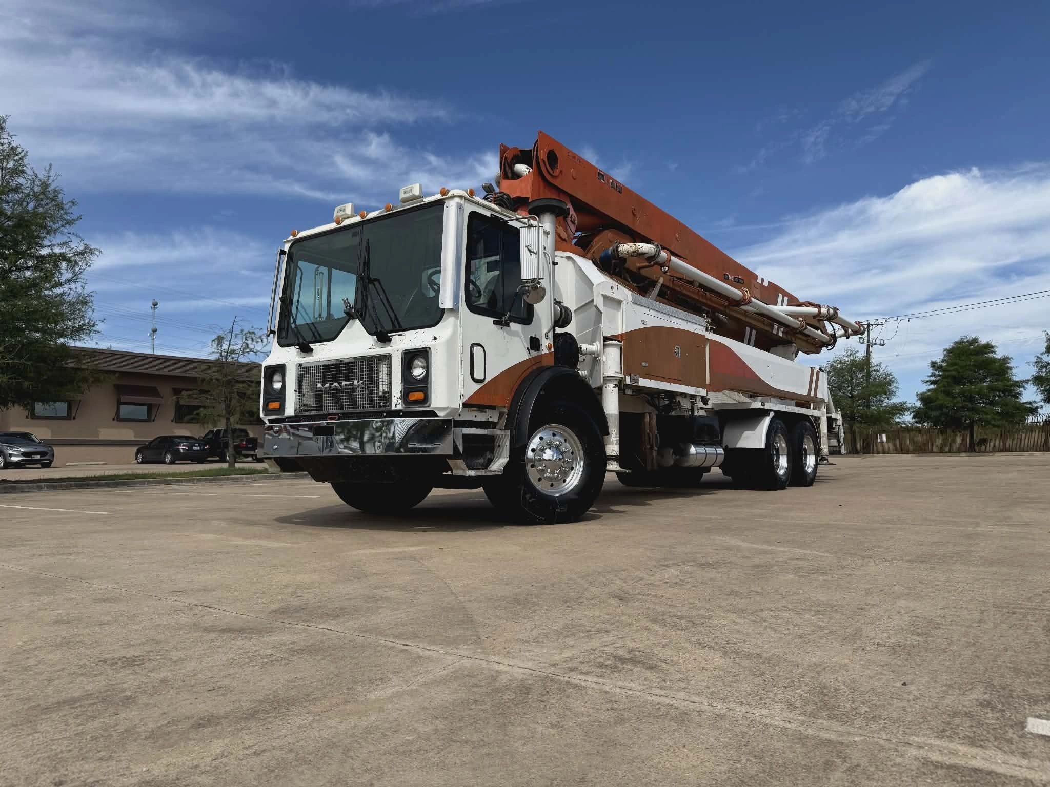 Large white and orange construction truck under a blue sky.