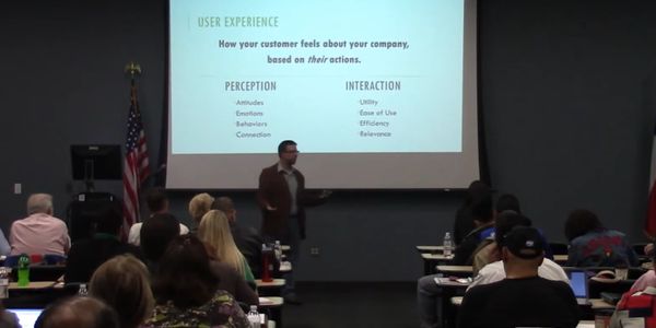 Presenter explains user experience concepts to an attentive audience in a classroom.