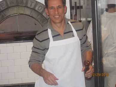Robert Realmuto smiling in a kitchen wearing a white apron.