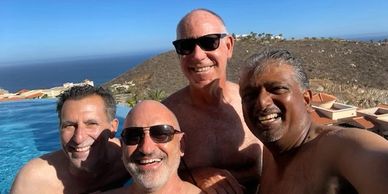 Robert Realmuto and friends smiling in a pool with an ocean view behind them.