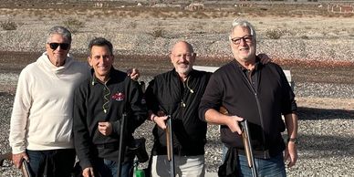 Robert Realmuto and friends pose with shotguns at an outdoor shooting range.
