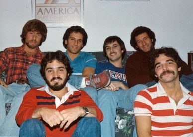 Young Robert Realmuto with friends relaxing on a couch in casual clothes.