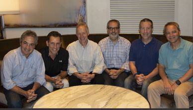 Robert Realmuto with friends gathered and smiling around a coffee table.
