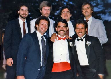 Robert Realmuto at a wedding in a tuxedo, smiling with longtime friends.
