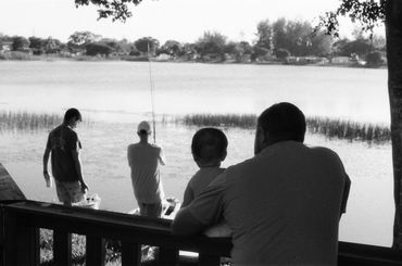 Family enjoying fishing by a lakeside in black and white.