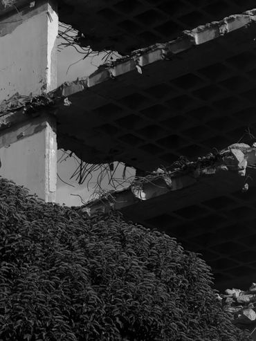Black and white photo of a partially demolished building with exposed concrete and rebar.