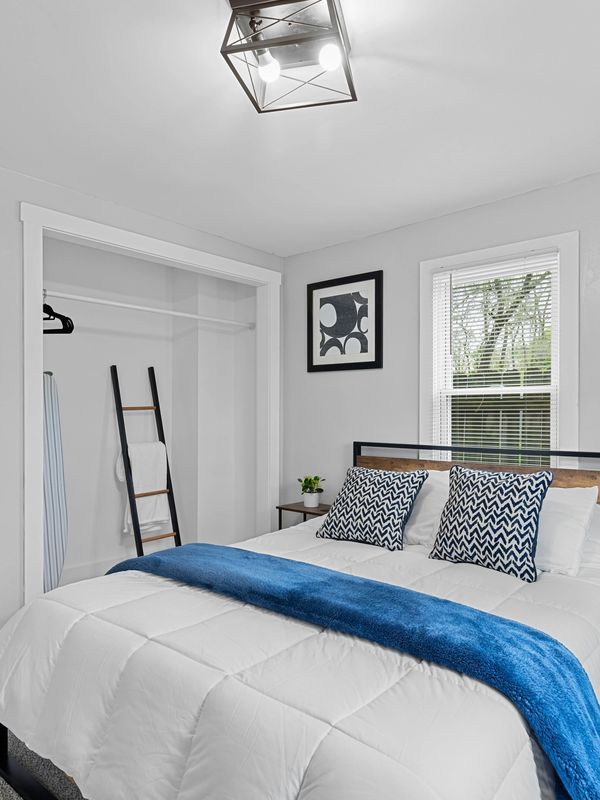 Minimalist bedroom with white walls, blue accents, and simple decor.