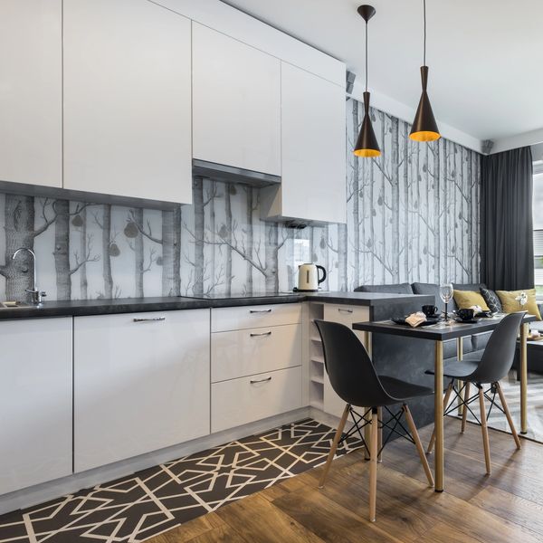 Modern kitchen-living space with white cabinets and black dining chairs.