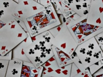 A scattered pile of playing cards featuring various suits and numbers.
