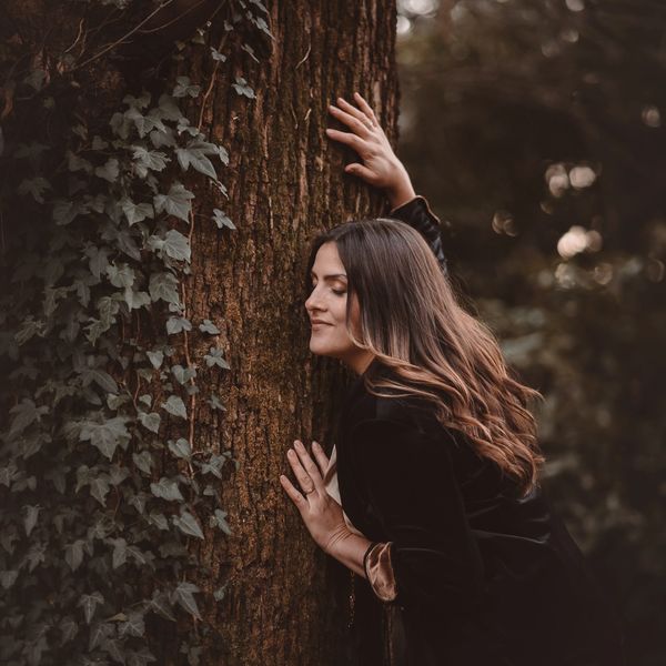 Donna che abbraccia un albero in un bosco.