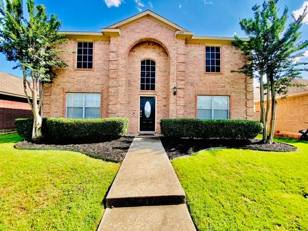 Brick two-story house with black door, symmetrical windows, and trimmed greenery. Landscaping work performed