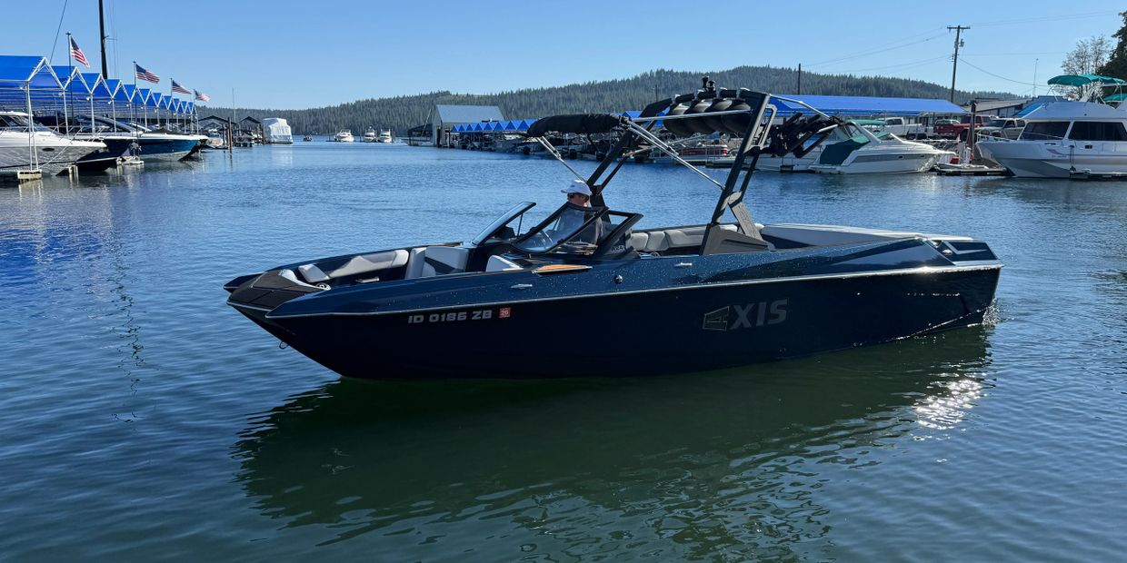 A sleek Axis motorboat on calm waters near a marina.