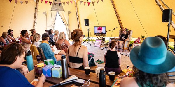 Group listens to speaker inside a decorated tent with bunting.