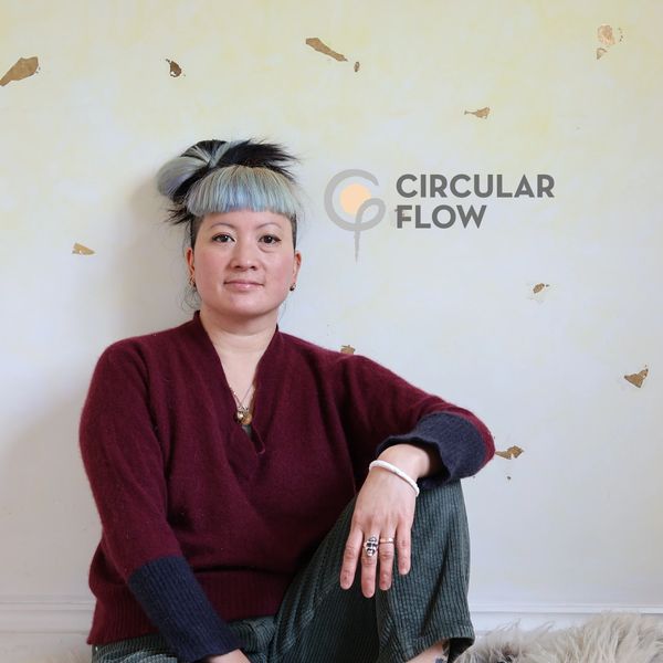 Person sitting casually against a wall with Circular Flow logo.