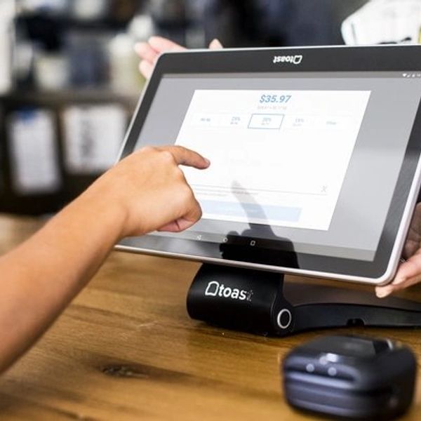 Person using a Toast POS touchscreen for payment.
