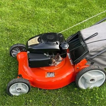 Orange and black lawn mower on green grass.