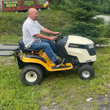 Man riding a Cub Cadet lawn tractor on grass.