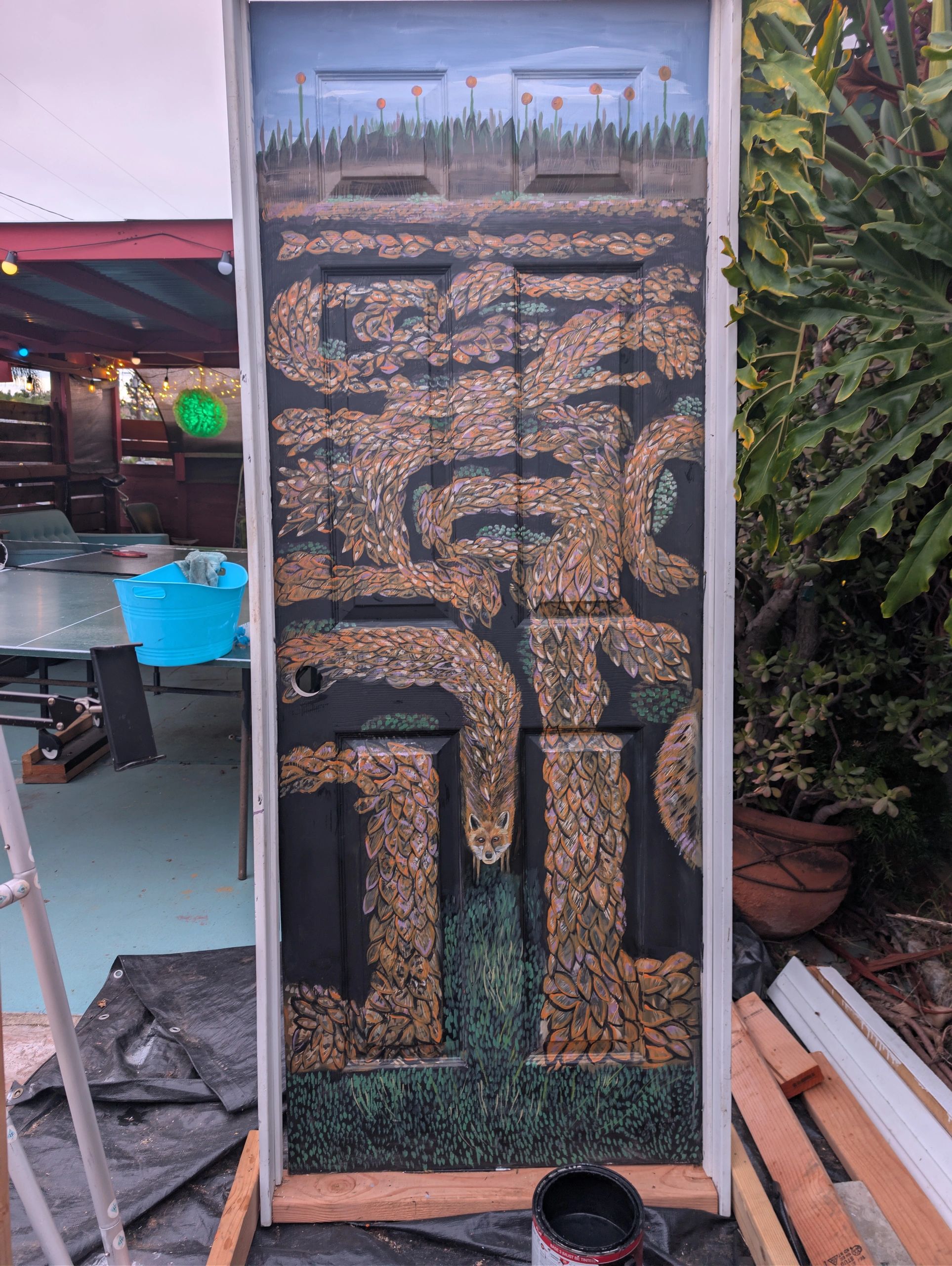 A door painted with an intricate design of intertwined leaves and a fox's face.