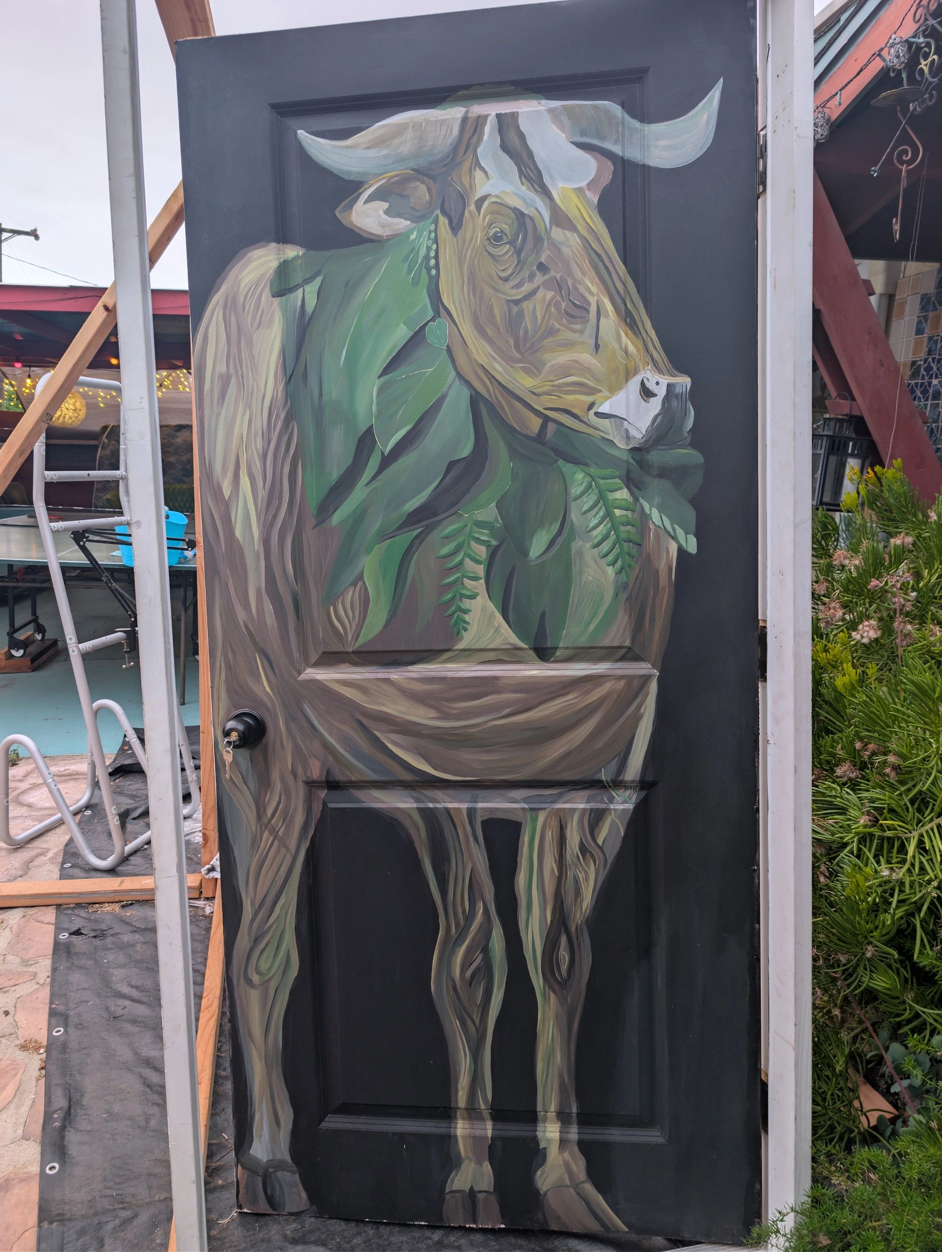 A painted door features a bull adorned with green leaves.