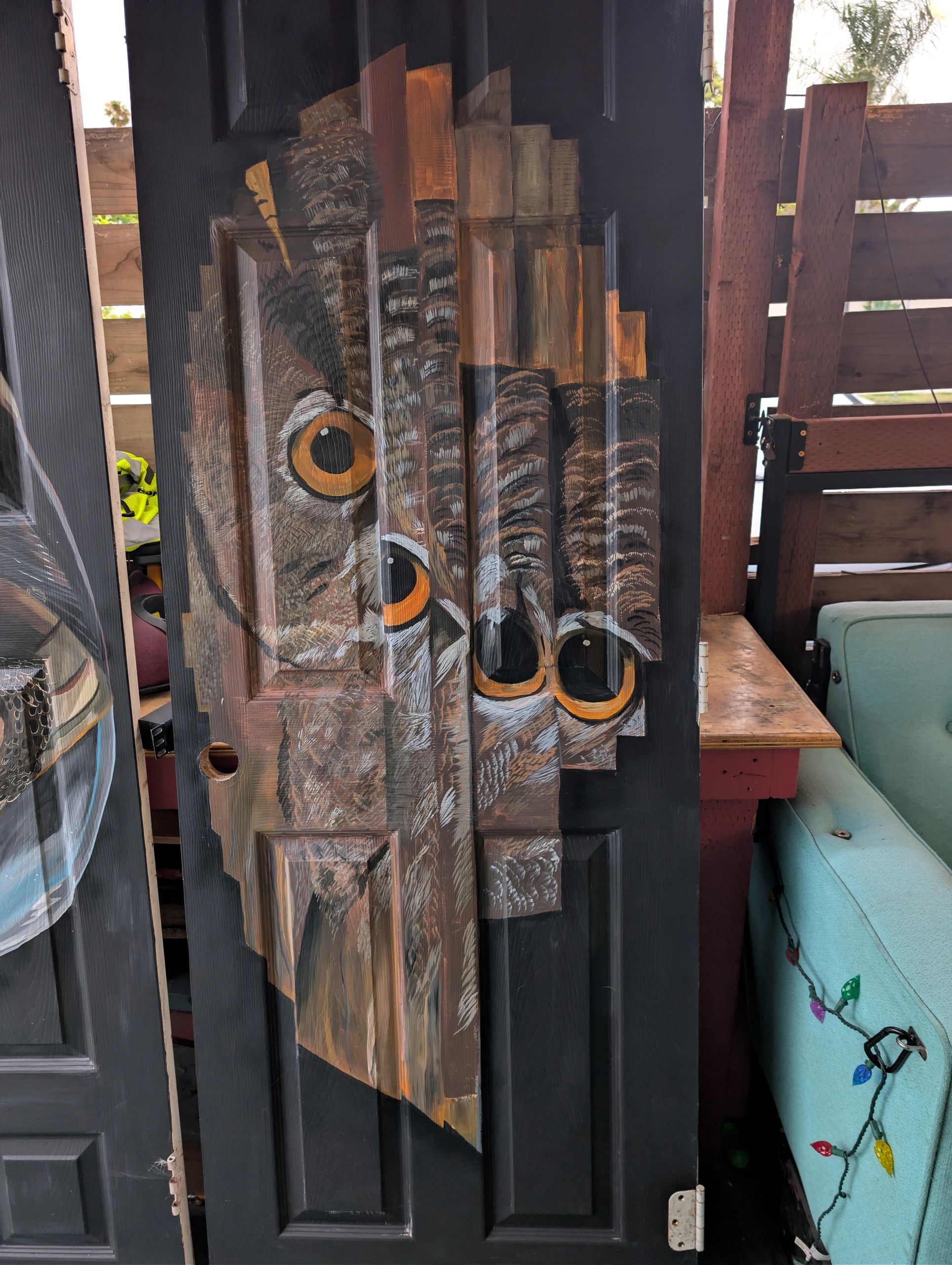 A painted owl on a black door with striking orange eyes.