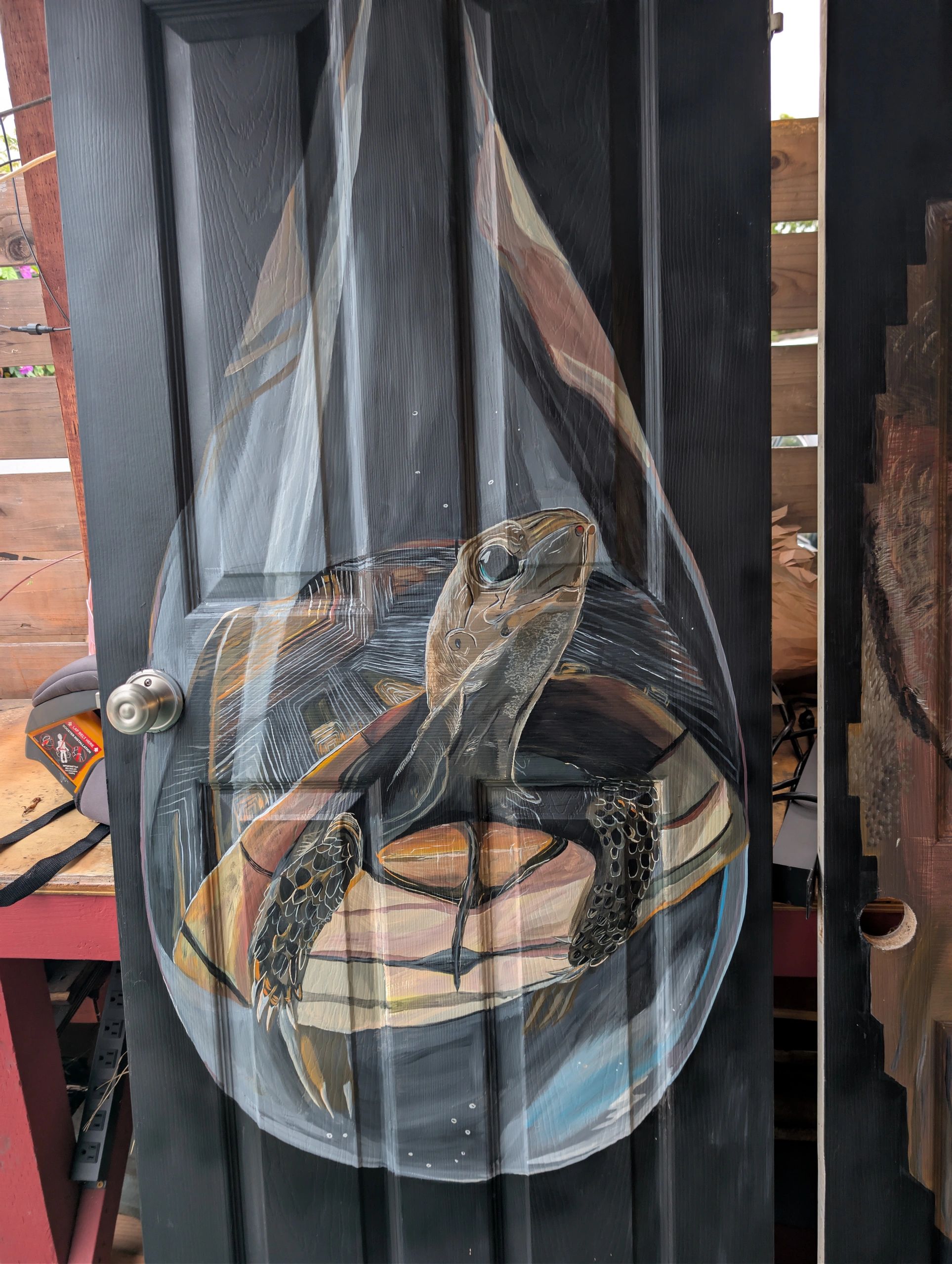 A detailed painting of a sea turtle inside a glass dome on a black door.