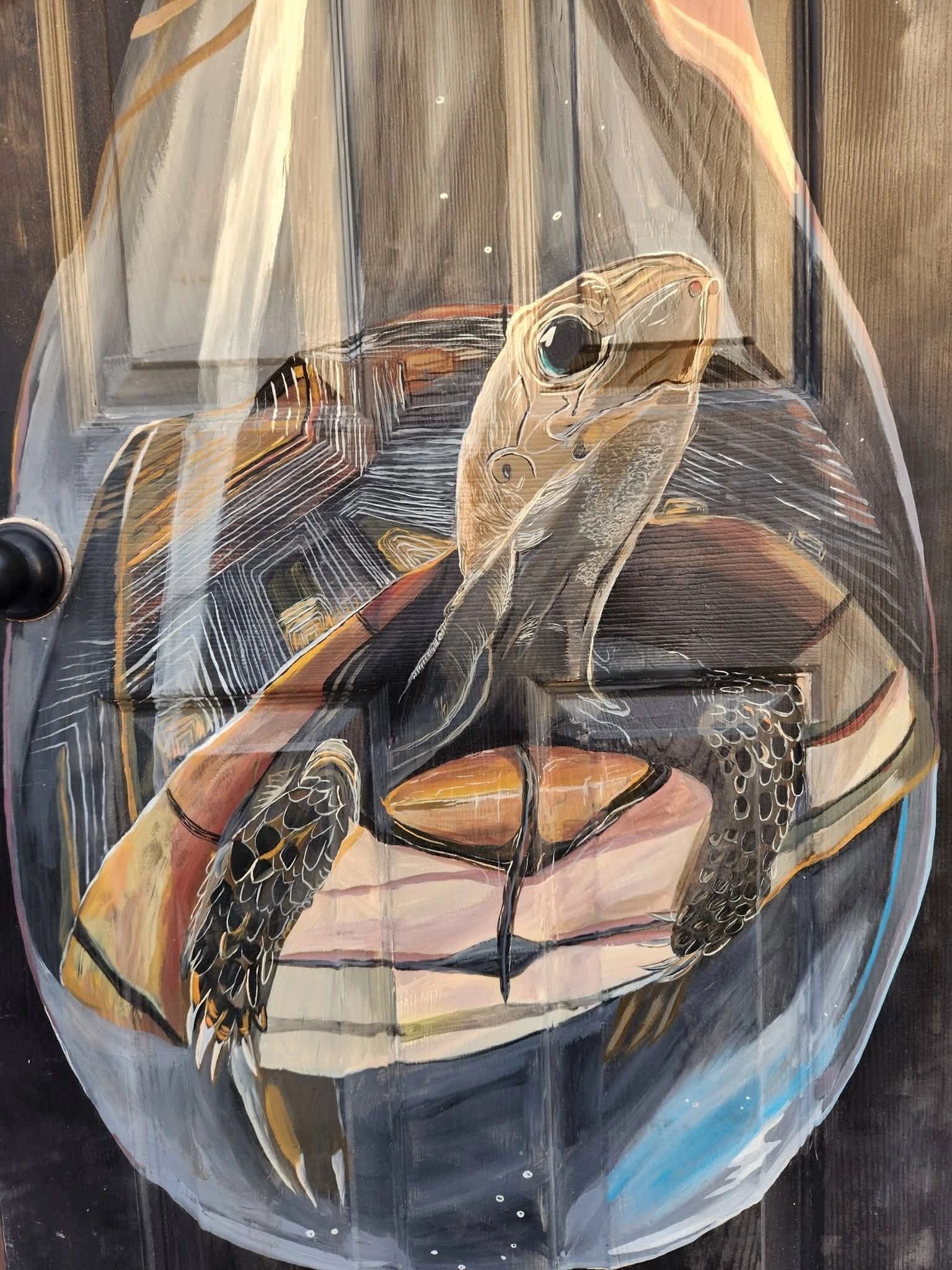 A detailed painting of a turtle inside a glass container on a wooden surface.