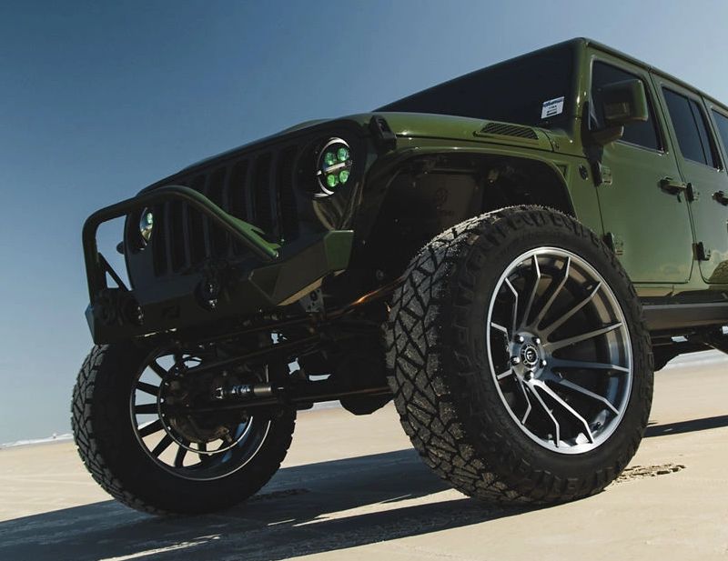 Green off-road Jeep on sandy terrain.
