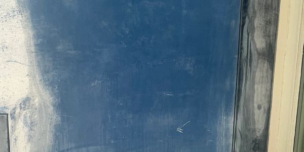 Blue wall with paint marks next to a window frame.
